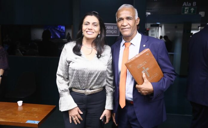 Um homem e uma mulher em pé lado a lado sorriem para a câmera