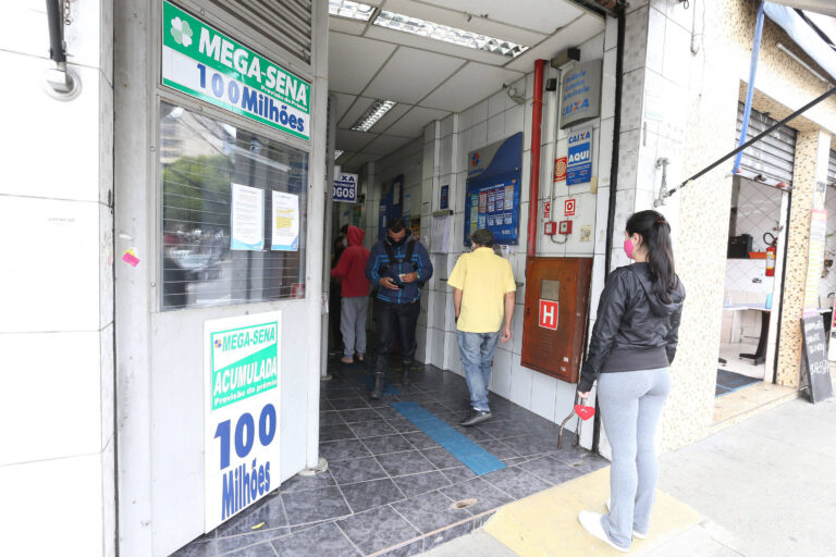 A imagem mostra a entrada de uma casa lotérica. Há um letreiro verde com a inscrição 