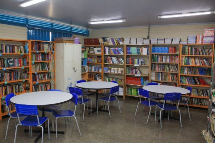 Biblioteca escolar - estantes com livros, mesas e cadeiras para leitura e estudo
