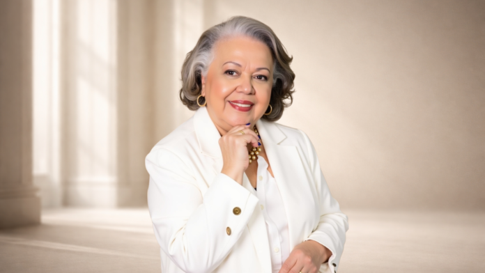 Myrinha Vasconcellos em retrato institucional, vestindo blazer branco, representando o conceito de longevidade ativa e protagonismo feminino.