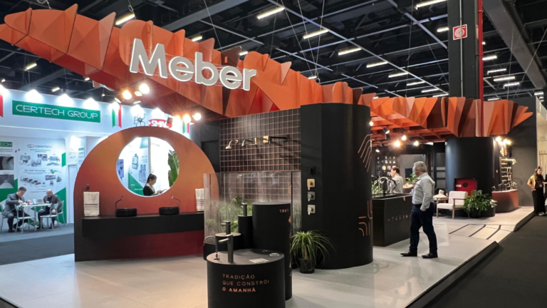 Estande da Meber Metais na Expo Revestir 2026 com estrutura ondulada em papel e exposição de torneiras e metais sanitários.
