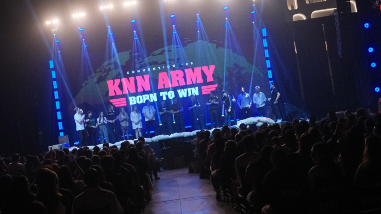 Palco da KNN Convention 2026 Born To Win com público lotado e equipe no palco durante encerramento do evento