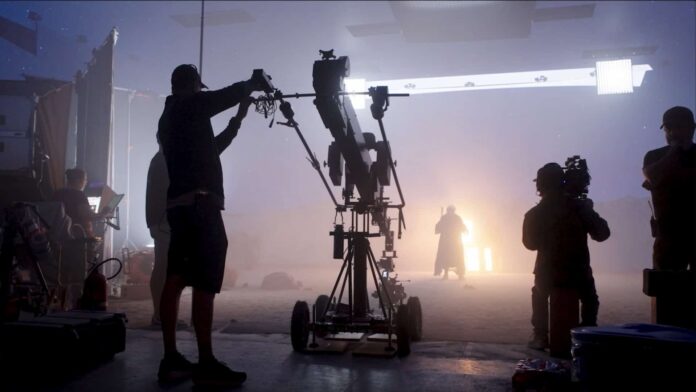 Técnico ajusta equipamento de câmera em estúdio de filmagem envolto em névoa