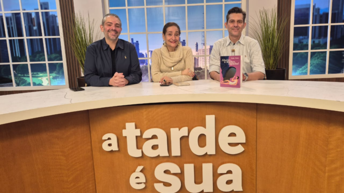 Expo Sonia Abrão em estúdio de TV ao lado de dois apresentadores, durante entrevista sobre sua carreira e o lançamento de livro, participação que antecede sua presença confirmada na Expo Empreendedor 2026.